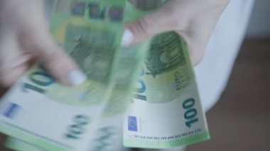Bir kadının 100 Euro 'luk banknotları sayarak mali işlemlerdeki ayrıntılara dikkat çeken ellerine yakından bakmak.