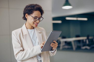 Gülümseyen kadın serbest yazar, dijital tablet üzerinde çalışıyor. 