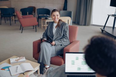 Yeni projede birlikte çalışan kadın yöneticiler ve ofiste oturan dizüstü bilgisayar ve dijital tablet kullanıyorlar