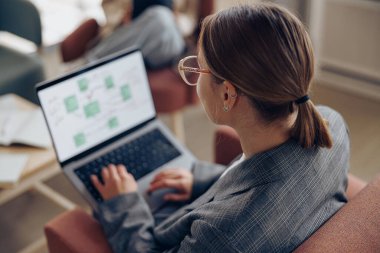 Meslektaşının geçmişi üzerinde çalışırken dizüstü bilgisayarda çalışan zarif bir bayan girişimci.