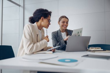 İki gülümseyen iş kadını bürodaki işi halletmek için belgelerle birlikte çalışıyorlar.