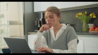 Modern bir mutfak ortamında dizüstü bilgisayarı üzerinde çalışan bir kadın son derece odaklanmış görünüyor. Bu görüntü, evden uzakta çalışırken konsantrasyon ve adanmışlığın özünü yakalar..