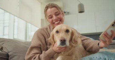 Genç bir kadın Golden Retriever 'ıyla şakalaşarak selfie çekiyor, tatlı bir ifadeyle dudaklarını büzüştürüyor. Neşeli an, kadın ve evcil hayvanı arasındaki sevgi ve bağın göstergesidir.