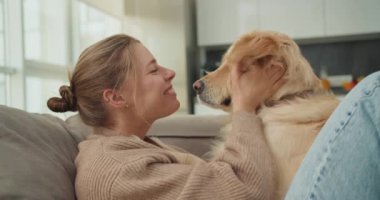Genç bir kadın köpekleri avucunun içinde tutarken köpeklerin gözlerine sevgiyle bakar. Bu hassas, sevecen an evcil hayvan ve sahibi arasındaki güçlü bağı vurguluyor.