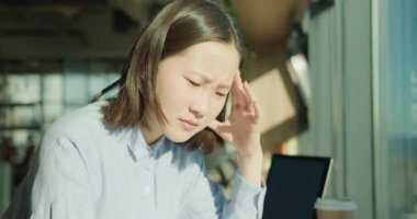 Genç bir kadın, modern ofis ortamındaki belgeleri analiz etmeye derinden odaklanmış olarak görülüyor. İfadesi kararlılığı ve problem çözmeyi yansıtıyor. Güneş ışığı sakin bir atmosfer yaratıyor..