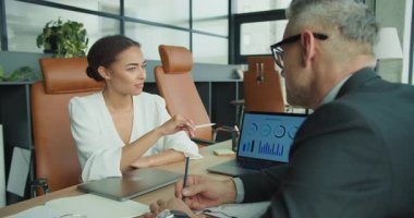 İş kadını ve işadamı, modern bir ofiste yapılan toplantı sırasında veri analizini tartışıyor ve bilgisayar ekranında bir bilgi ekranında görüntüleniyor..