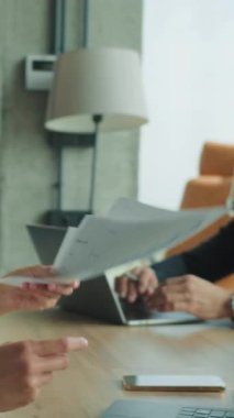 İş adamı ve iş kadını, toplantı sırasında modern bir ofis masasında evrak alışverişinde bulunuyorlar. Dizüstü bilgisayarları, grafikleri ve kahve fincanları olan profesyonel bir ortam..