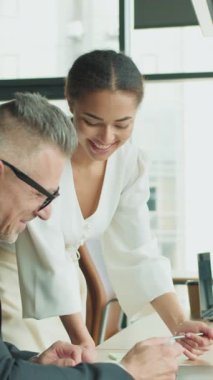 İş adamı ve iş kadını modern ofis masasında iş birliği yapıyorlar. Bayan meslektaşım ekranı işaret ederken gülümsüyor. Şirket ortamında profesyonel takım çalışması.