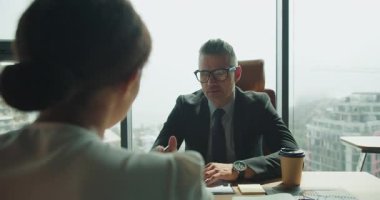 Düşünceli bir işadamı, stratejik bir iş tartışması sırasında, modern bir gökdelendeki meslektaşını dikkatle dinler..