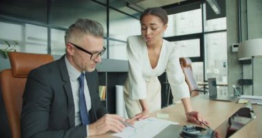 Kendine güvenen iş kadını, modern ofis ortamındaki bir erkek meslektaşına finansal verileri açıklıyor. Belgelere odaklı bir iş toplantısında takım işbirliği.