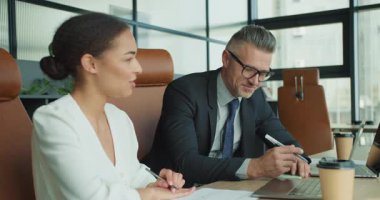 İş kadını düşüncelerini paylaşırken, iş adamı da gündelik ama odaklı bir toplantıda laptoplar, çizelgeler ve kahveyle gündelik bir toplantı yapıyor..