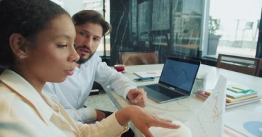 Bir iş kadını, bir toplantı sırasında iş arkadaşına satış çizelgelerini sunar. Modern ofis ortamında çalışırken grafikleri inceler ve performans verilerini tartışırlar. Yüksek kalite 4k görüntü