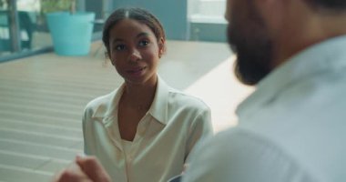 Krem rengi bluzlu kendine güvenen genç iş kadını iş yerindeki sıradan bir konuşma sırasında erkek bir meslektaşını dikkatle dinliyor. Doğal ışıklandırmayla modern ofis içi. Yüksek kalite 4k görüntü