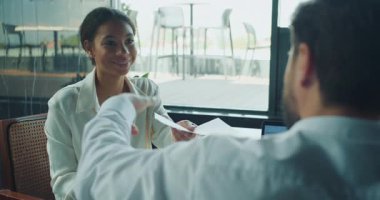 Gülümseyen iş kadını, parlak, modern bir ofiste yaptığı toplantıda yazılı mali belgeleri erkek arkadaşına teslim etti. Profesyonel takım çalışması ve pozitif işbirliği ortamı. Yüksek kalite