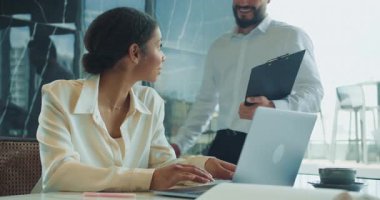 Modern, parlak bir ofis alanında dizüstü bilgisayarla çalışan odaklanmış bir iş kadını. Elinde bir fincan, bir defter ve sakin bir profesyonel tavırla temiz bir masada oturuyor. Yüksek kalite 4k görüntü