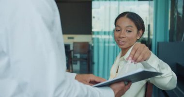 İş kadını, bir meslektaşı modern bir ofiste yaptığı toplantıda verileri pano kullanarak açıklarken dikkatle dinliyor. Profesyonel iş yeri işbirliği sahnesi. Yüksek kalite 4k görüntü