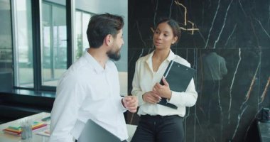 Kendine güvenen işadamı ve iş kadını şık bir ofis ortamında, klasörler ve dizüstü bilgisayarlar tutarken profesyonel bir ortamda fikirleri paylaşıyorlar. Yüksek kalite 4k görüntü