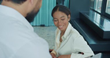 Kendine güvenen bir iş kadını modern bir ofiste bir meslektaşıyla konuşurken gülümser. Görüntü, profesyonel bir ortamda takım çalışması, güven ve pozitif iletişimi yakalar. Yüksek kalite 4k görüntü