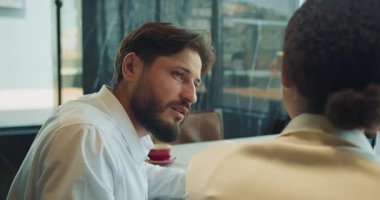 Beyaz gömlekli bir işadamı modern bir ofiste bir iş arkadaşını dikkatle dinler. Atmosfer odaklanmış, düşünceli bir iş sohbetini çağrıştırıyor. Yüksek kalite 4k görüntü