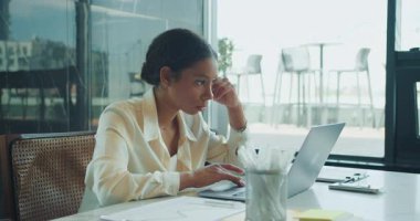 Parlak bir ofis masasında dizüstü bilgisayarda çalışan genç bir iş kadını, etrafındaki belgeler ve modern çalışma alanı unsurlarıyla verileri derinden inceliyor ve analiz ediyor. Yüksek kalite 4k görüntü