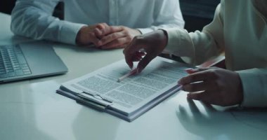 Bir erkek ve kadının iş kıyafetleri içinde bir masada dizüstü bilgisayar ve elinde yasal bir kontrat tutan bir panoyla çekilmiş yakın plan fotoğrafları. Elleri sımsıkı bağlanmış, imzalamadan önce bir tartışma öneriliyor. Yüksek kalite