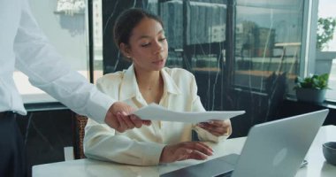 Beyaz bluzlu bir iş kadını bir masada oturur ve dizüstü bilgisayarına konsantre olur. Modern ofis ortamında tek eliyle başını destekliyor. Yüksek kalite 4k görüntü