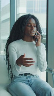 Genç bir birey, aydınlık ve modern bir ofis ortamında otururken duygusal bir telefon görüşmesi yapar.