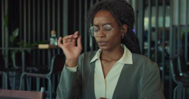 Profesyonel kıyafetli odaklanmış bir kadın modern ofis ortamında özenle dizüstü bilgisayarı üzerinde çalışıyor.