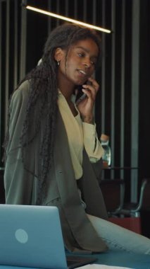 Çağdaş bir ofis ortamında çalışırken odaklanmış genç bir profesyonel telefonda konuşur..