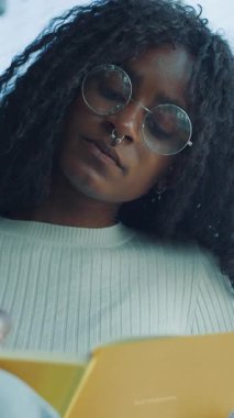 Yumuşak doğal ışık altında okumaya dalmış, yaratıcılığını güzelce gösteren ve rahat bir ortama odaklanan bir insan.