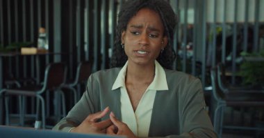 Kendini işine adamış bir profesyonel, şık bir ofis ortamında yapılan sanal bir toplantıda yenilikçi fikirleri ifade eder.