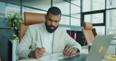 Modern bir ofiste, odaklanmış bir profesyonel bilgisayarını etkin bir şekilde kullanırken karmaşık çizelgeleri analiz eder.