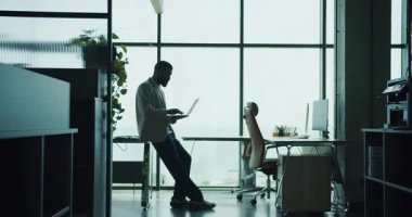 Modern ofis ortamında özenle bir dizüstü bilgisayara odaklanmış bir birey verimliliğini gösteriyor.