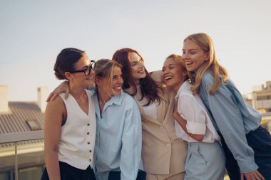 Neşeli bir arkadaş grubu, birlikte güzel, güneşli bir günü kucaklıyor, dostluğun ve kahkahanın özünü vurguluyor.