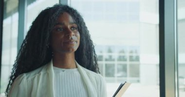 Kendine güvenen bir iş kadını modern bir ofis ortamını düşünceli bir şekilde meşgul ederken şık bir defter tutar.