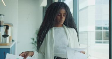 Parlak ve modern bir ofiste, sakin bir atmosferi olan, odaklanmış bir kadın, önemli belgeleri özenle gözden geçirir.