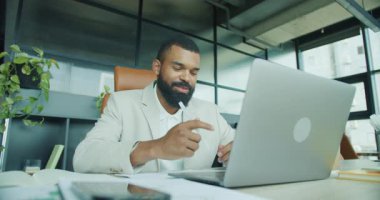 Modern ofis ortamında kendini işine adamış bir işadamı, detaylı notlar alırken bilgisayarına çok bağlıydı.