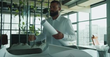 Yetenekli bir profesyonel modern ofis ortamında karmaşık mimari planları dikkatlice inceler.