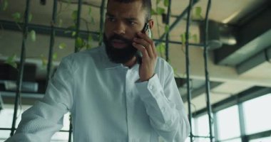 Bir iş adamı yemyeşil bir ofiste akıllı bir telefon görüşmesi yapar.