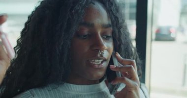 Güzel kıvırcık saçlı genç bir kadın havaalanında canlı bir telefon görüşmesi yapıyor.