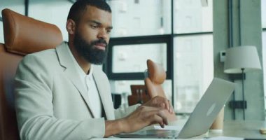 Modern ofis ortamında bir dizüstü bilgisayarda çok dikkatli bir şekilde görev yapan bir profesyonel.