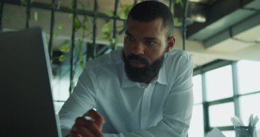 Beyaz gömlekli kendini işine adamış bir adam modern bir ofiste profesyonelliğini sergiliyor..