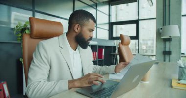 Kendini işine adamış bir profesyonel, dizüstü bilgisayar kullanırken modern ve şık bir ofis kurar.