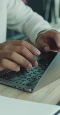 Yakın çekim görüntüsü, modern ve çağdaş ofis ortamı içindeki parlak bir dizüstü bilgisayarda aktif olarak yazı yazan elleri yakalar