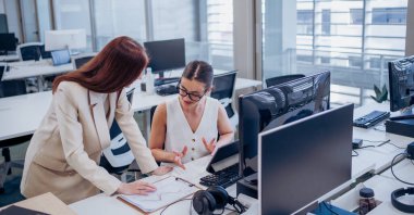 İki yetenekli profesyonel modern, iyi donanımlı ofis ortamında proje detaylarını derinden tartışıyorlar.