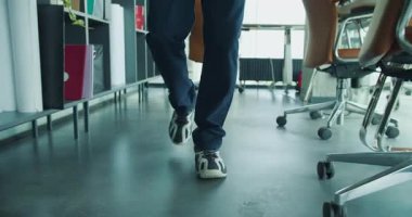 Kendine güvenen bir iş adamı, dizüstü bilgisayar taşırken kasıtlı olarak modern ofis alanından geçer.