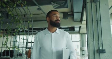 Kendini işine adamış ve odaklanmış bir profesyonel modern ve çağdaş bir ofis alanında rahatça yürüyor.