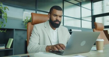 Kendini işine adamış bir profesyonel, özenle bilgisayarına odaklanmış, modern ofis ortamında çalışmaya dalmış.