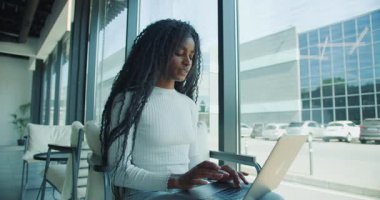 Genç bir kadın, dizüstü bilgisayarıyla yaratıcı şeylerle dolu parlak ve çağdaş bir ofis alanında derinden meşgul.