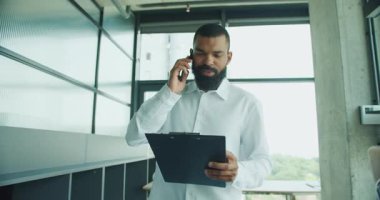 Modern, çağdaş bir ofis ortamında bir pano tutarken bir iş adamı bir telefon görüşmesi yaptı.